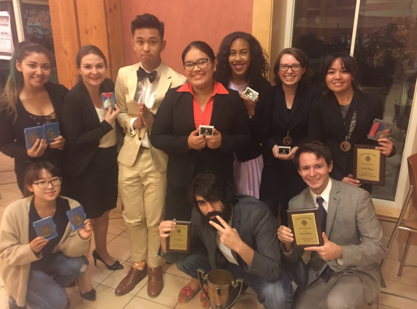 dvc 2017 speech and debate team. Students smilling, standing, holding awards and trophy. 