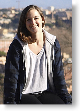Katelynn Cunningham, young woman smiling, sitting on a ledge in Italy