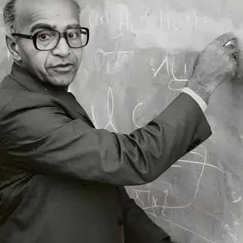 Black and white photo of Dr. David Blackwell holding a piece of chalk, writing a math equation on a chalkboard.