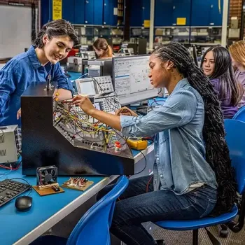Teacher watching student troubleshoot an electronic using a diagnostics machine.