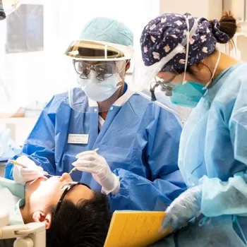 Two dental students working on a patient
