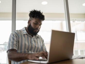Student working on laptop while going to college remotely from home